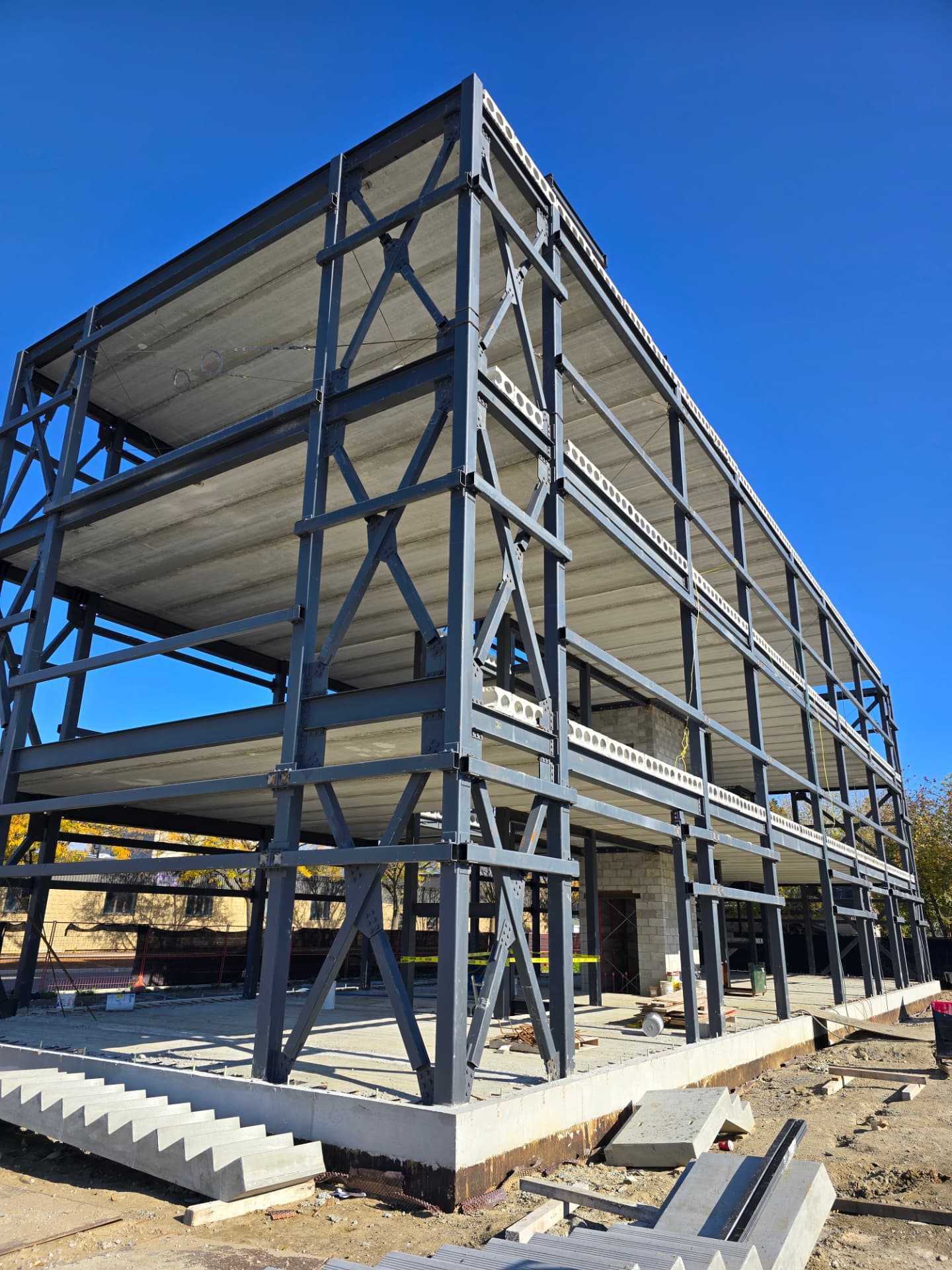 Three-story structural skeleton with wide-flange columns, chevron bracing and cellular beams over precast slabs