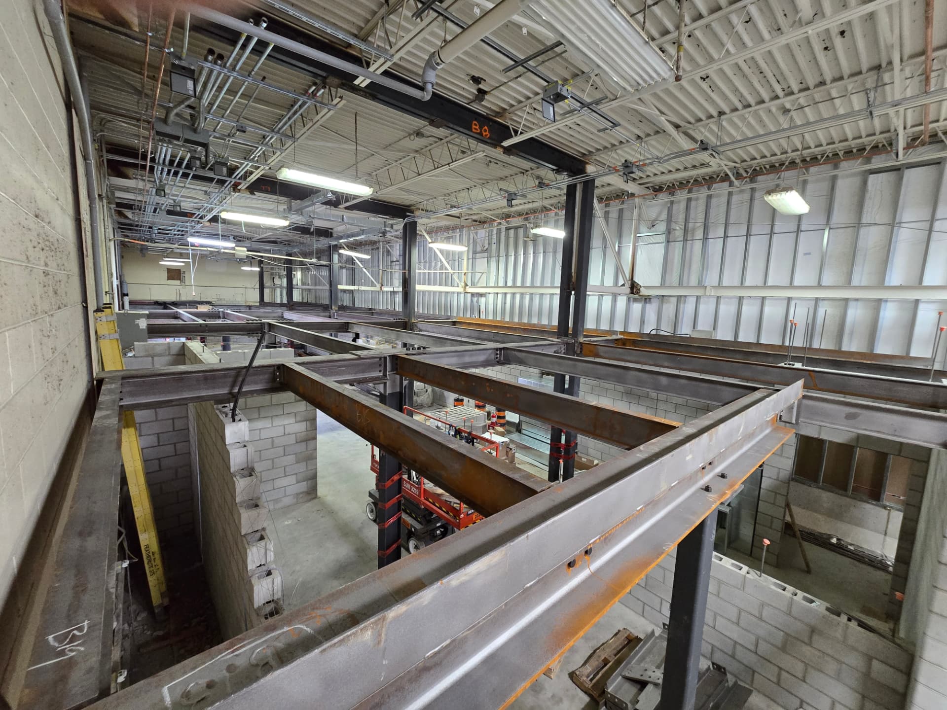 Interior mezzanine steel framing with open-web joists, roof trusses and corrugated deck