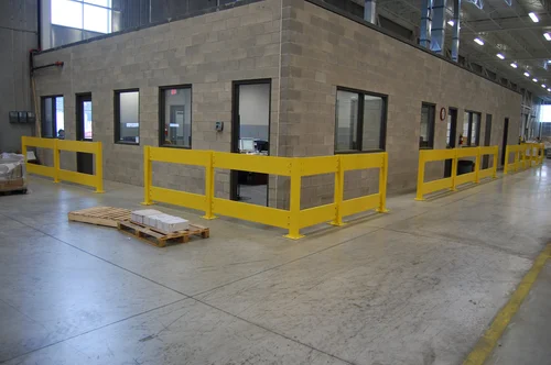 Yellow painted steel guardrails bolted to a warehouse floor